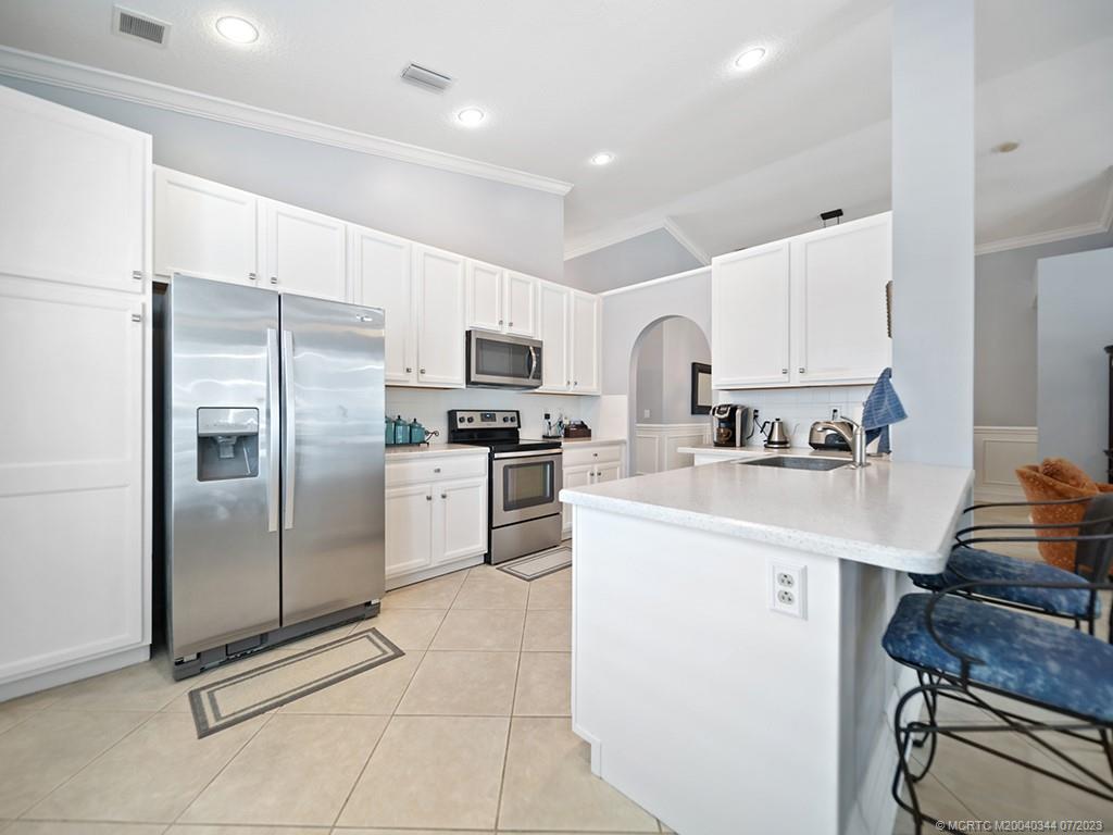 1136 Southeast Westminster Place Stuart, FL 34997 - Photo 18 of 36 a kitchen with stainless steel appliances a refrigerator sink and white cabinets
