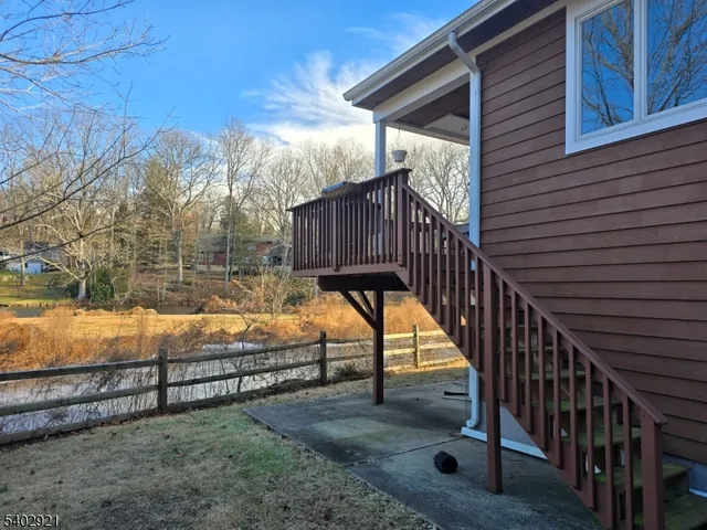 a view of backyard with a small deck and wooden fence