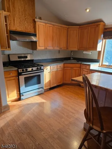 a kitchen with granite countertop a stove a sink and a microwave