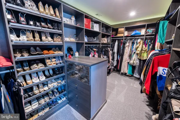 a view of walk in closet with clothes and shoes
