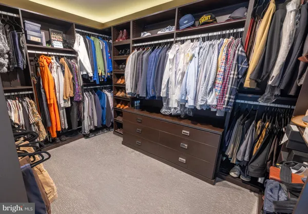 a view of walk in closet with clothes and shoes
