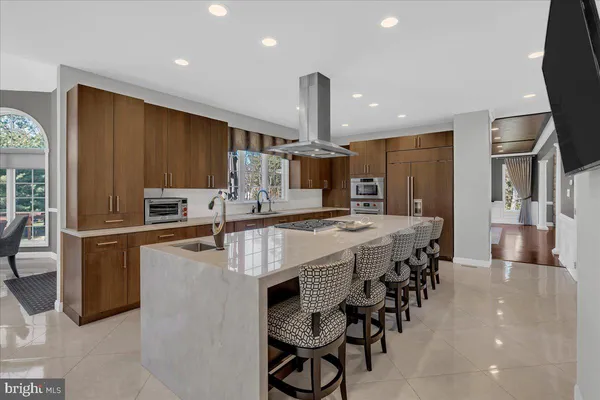 a large kitchen with lots of counter space a sink refrigerator and chairs