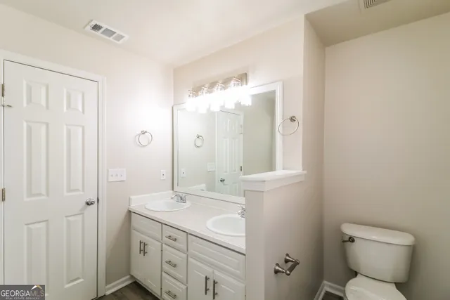 a bathroom with a granite countertop sink a toilet and a mirror