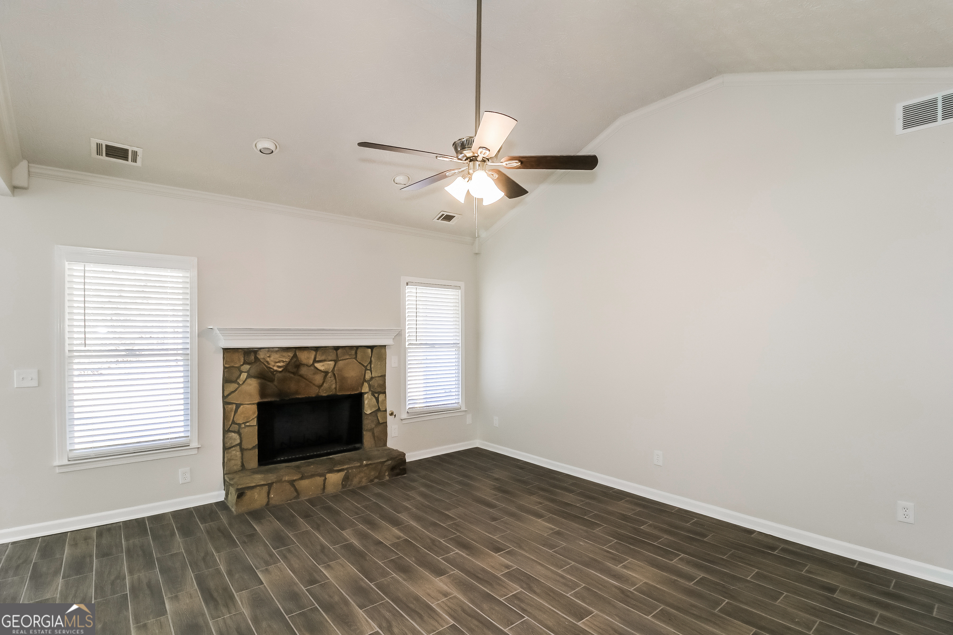 355 Freeman Drive Covington, GA 30016 - Photo 4 of 17 an empty room with windows a fireplace and a ceiling fan