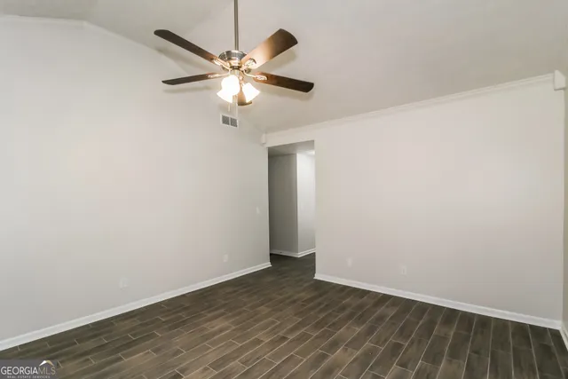 an empty room with wooden floor closet and fan