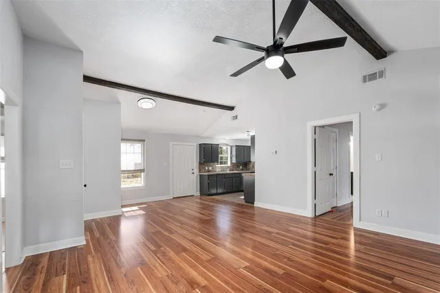 a view of empty room with kitchen and window