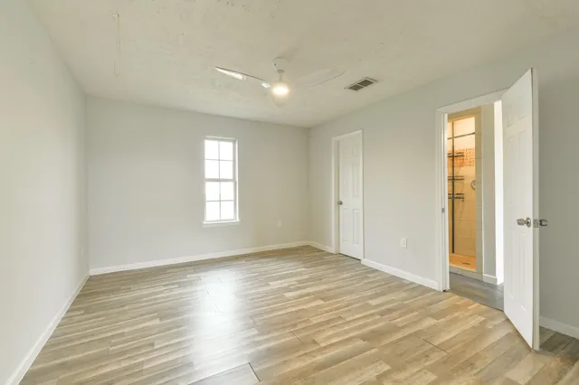 a view of empty room with wooden floor and fan