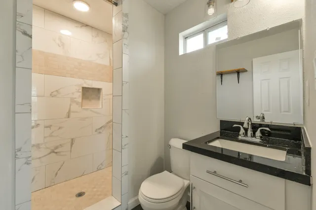 a bathroom with a sink a toilet a mirror and shower