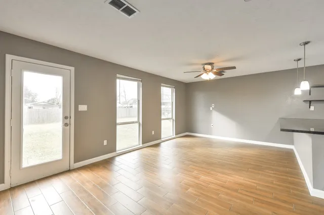 a view of an empty room with window and wooden floor