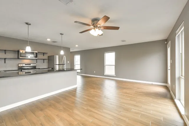 a view of a kitchen with a stove cabinets a ceiling fan and wooden floor