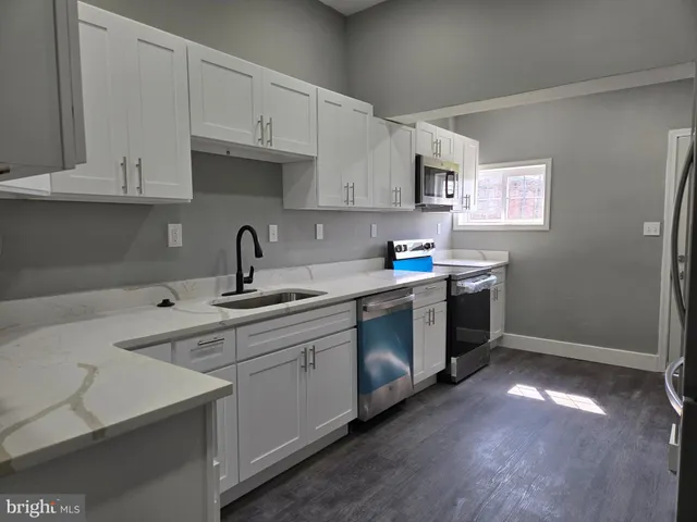 a kitchen with stainless steel appliances granite countertop a sink a stove a refrigerator and cabinets