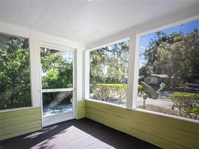 an empty room with wooden floor staircase and windows