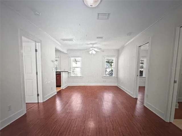 an empty room with wooden floor and windows