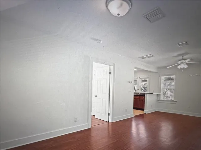 an empty room with wooden floor & windows and bathroom