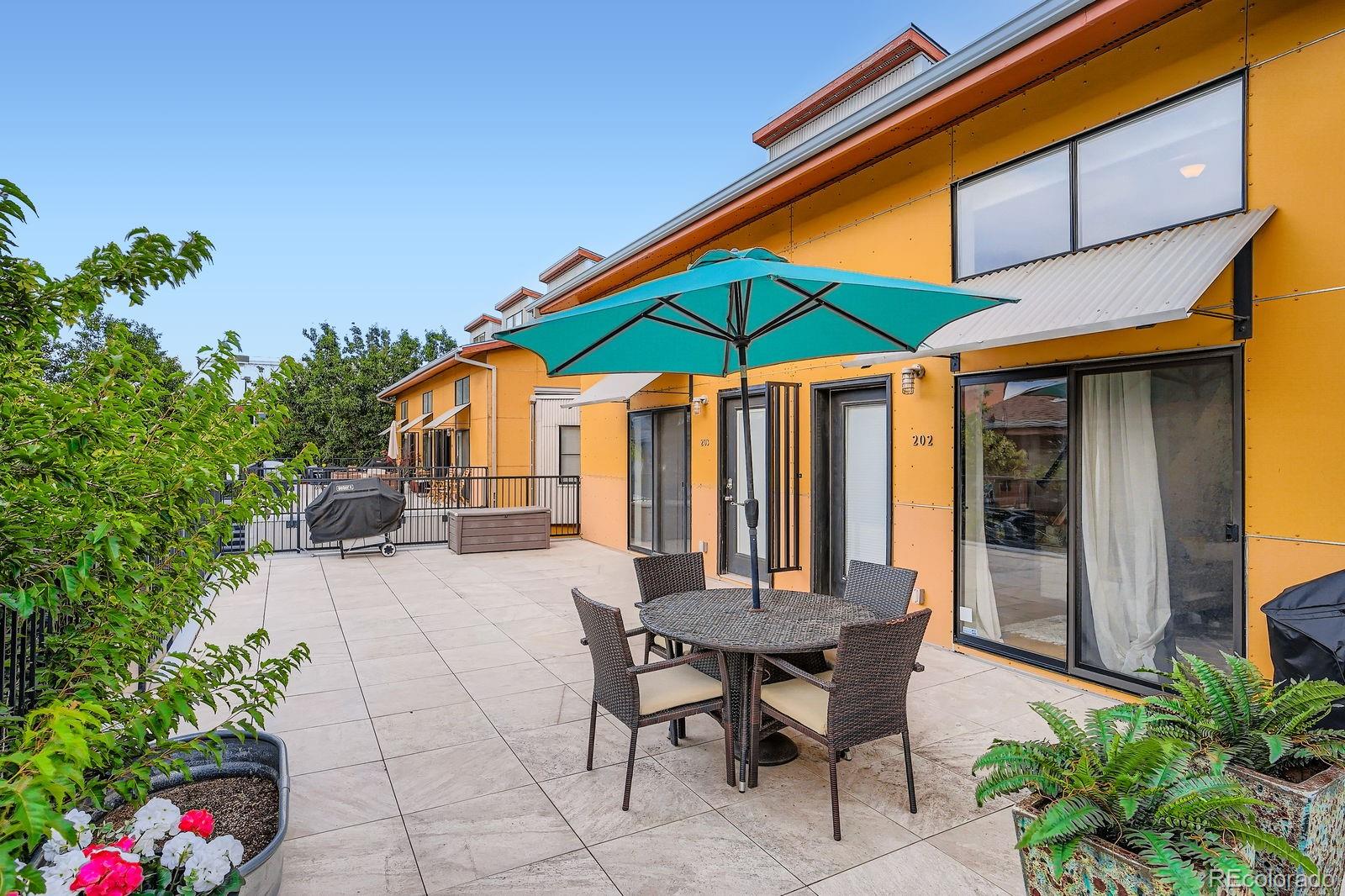 3295 Blake Street, Unit 202 Denver, CO 80205 - Photo 26 of 39 a patio with a table and chairs under an umbrella