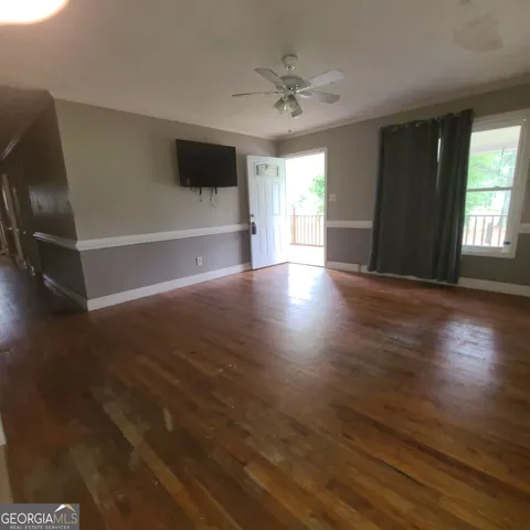 an empty room with wooden floor fan and windows