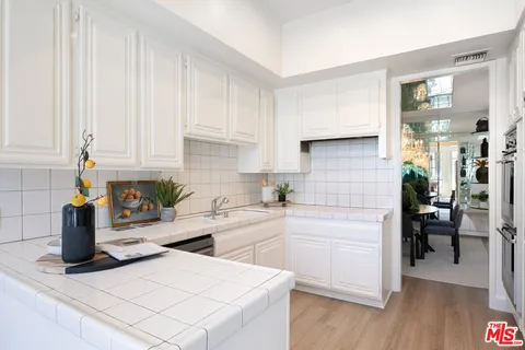 a kitchen with a white cabinets and wooden floor
