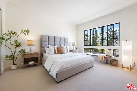 a bedroom with a bed couch and a large window