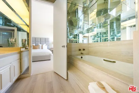 a bathroom with a tub a sink and a large mirror next to a window