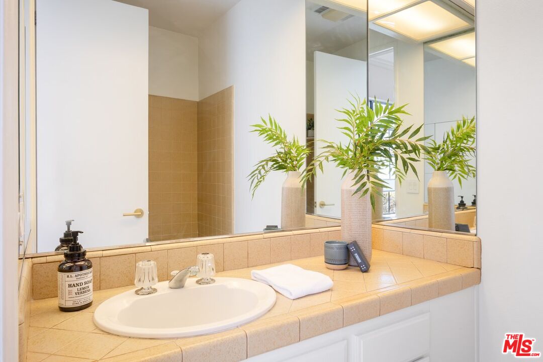 457 North Doheny Drive, Unit 304 Beverly Hills, CA 90210 - Photo 25 of 32 a bathroom with a granite countertop sink a mirror and a