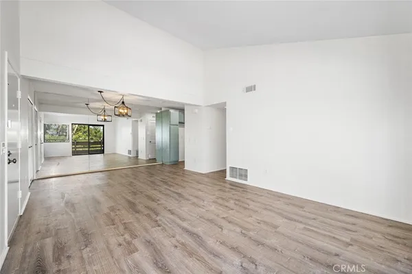 a view of an empty room with a window and a kitchen view