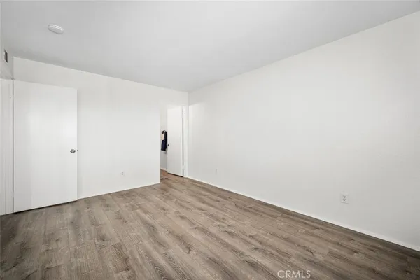 a view of an empty room with wooden floor and a bathroom