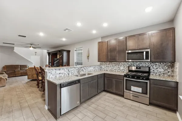 a kitchen with stainless steel appliances granite countertop a stove top oven a sink and a refrigerator