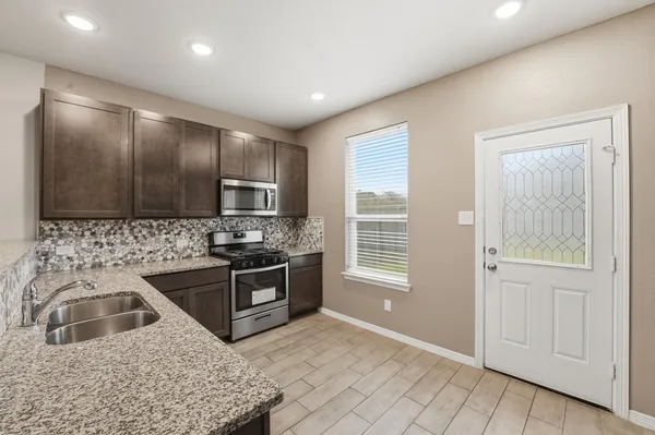a kitchen with stainless steel appliances granite countertop a sink stove and refrigerator