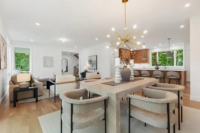 a view of a dining room and livingroom with furniture a rug a fireplace and a chandelier