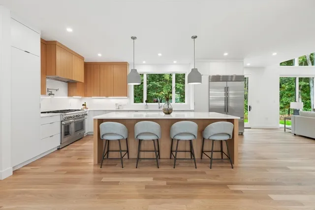 a kitchen with stainless steel appliances granite countertop a stove top oven a sink dishwasher and white cabinets with wooden floor