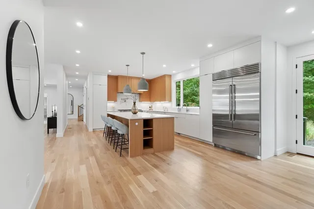 a large kitchen with a large counter top a sink stainless steel appliances and cabinets