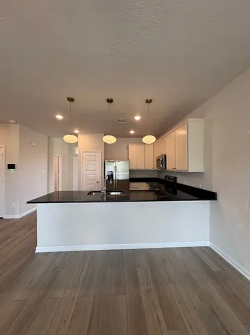 a large kitchen with stainless steel appliances a large counter top a sink and a wooden floor