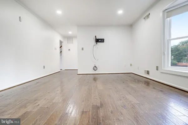 a view of an empty room with a fireplace and wooden floor