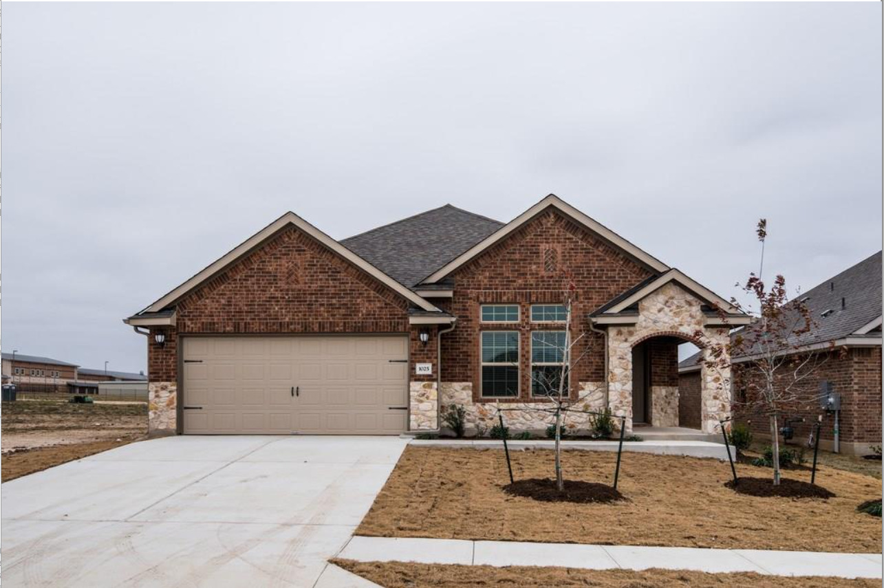 Brick and stone facade featuring an arched entryway, gabled rooflines, and a two-car garage