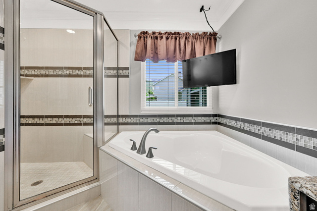 4792 Glasmann Way South Ogden, UT 84403 - Photo 34 of 70 Primary ensuite with built-in soaking tub with a tiled surround, complemented by a glass-enclosed shower featuring a tiled bench and mosaic accent banding and a television