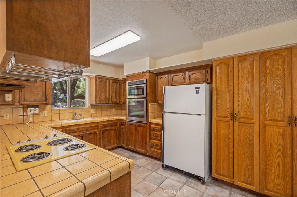 32413 Chickasaw Road Coarsegold, CA 93614 - Photo 23 of 66 a kitchen with stainless steel appliances granite countertop a refrigerator a sink and white cabinets