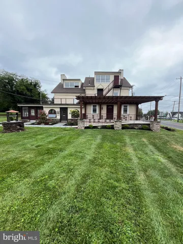a view of a house with a big yard and large trees