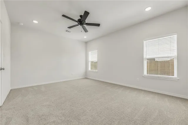 a view of a livingroom with a ceiling fan & windows