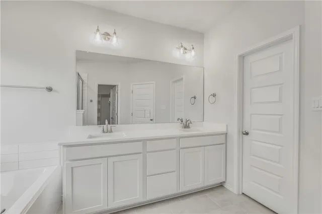 a bathroom with a double vanity sink a mirror and a bathtub