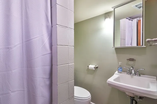 a bathroom with a sink a toilet and shower curtain