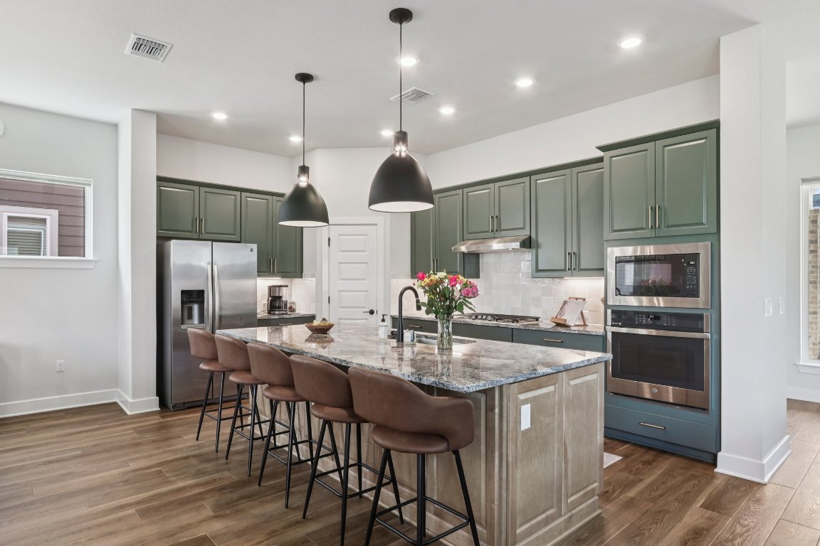 6001 McMurtry Street Austin, TX 78747 - Photo 6 of 26 a kitchen with stainless steel appliances granite countertop a kitchen island a stove a table and chairs in it