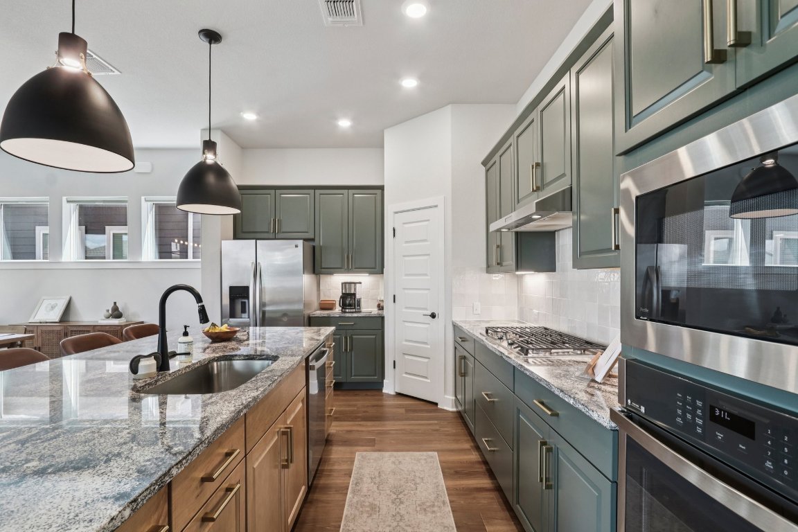 6001 McMurtry Street Austin, TX 78747 - Photo 7 of 26 a kitchen with stainless steel appliances granite countertop a sink stove and cabinets
