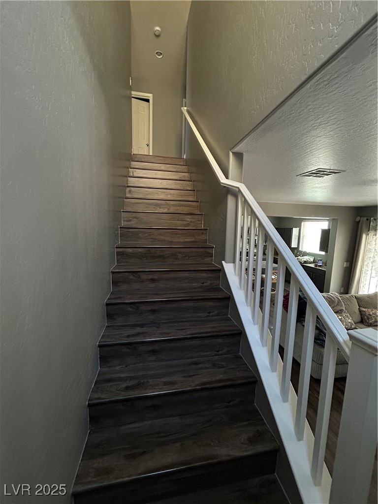 8977 Melridge Road Las Vegas, NV 89148 - Photo 22 of 35 Staircase featuring a textured wall and wood finished floors