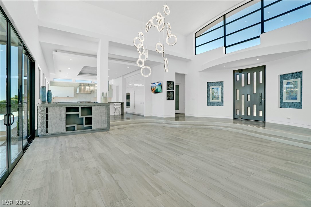 10 Ridge Blossom Road Las Vegas, NV 89135 - Photo 16 of 64 Unfurnished living room featuring a chandelier, a high ceiling, light wood-style floors, and recessed lighting