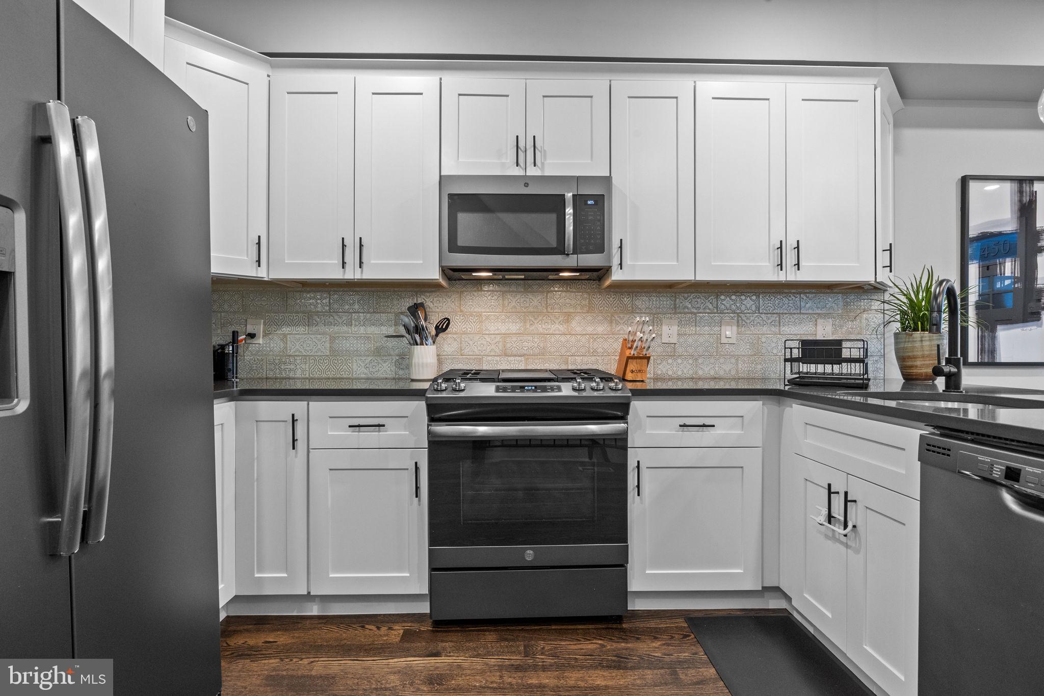 450 Ripka Street Philadelphia, PA 19128 - Photo 11 of 47 a kitchen with stainless steel appliances granite countertop a stove a microwave and a white cabinets
