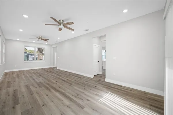 an empty room with wooden floor windows and ceiling fan