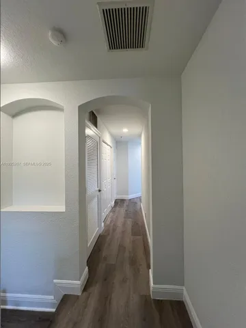a view of a hallway with wooden floor and a bathroom