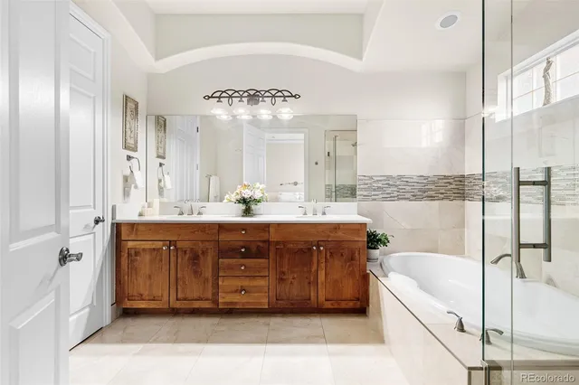 a spacious bathroom with a double vanity sink a tub and a large mirror