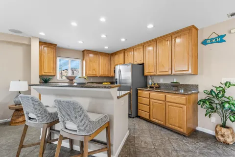 a kitchen with stainless steel appliances granite countertop a refrigerator a sink a stove a dining table and chairs