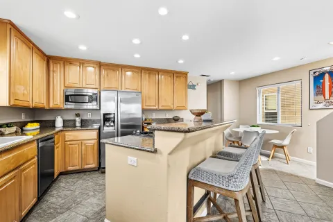 a large kitchen with kitchen island granite countertop a stove a sink a dining table and chairs